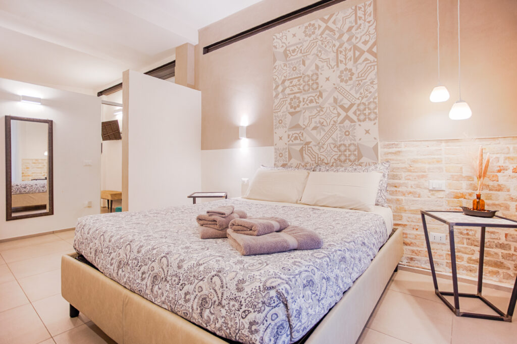 Camera suite matrimoniale di design al B&B Fontanella 32 di Porto Sant'Elpidio con letto matrimoniale, parete decorata in maiolica e mattoni a vista