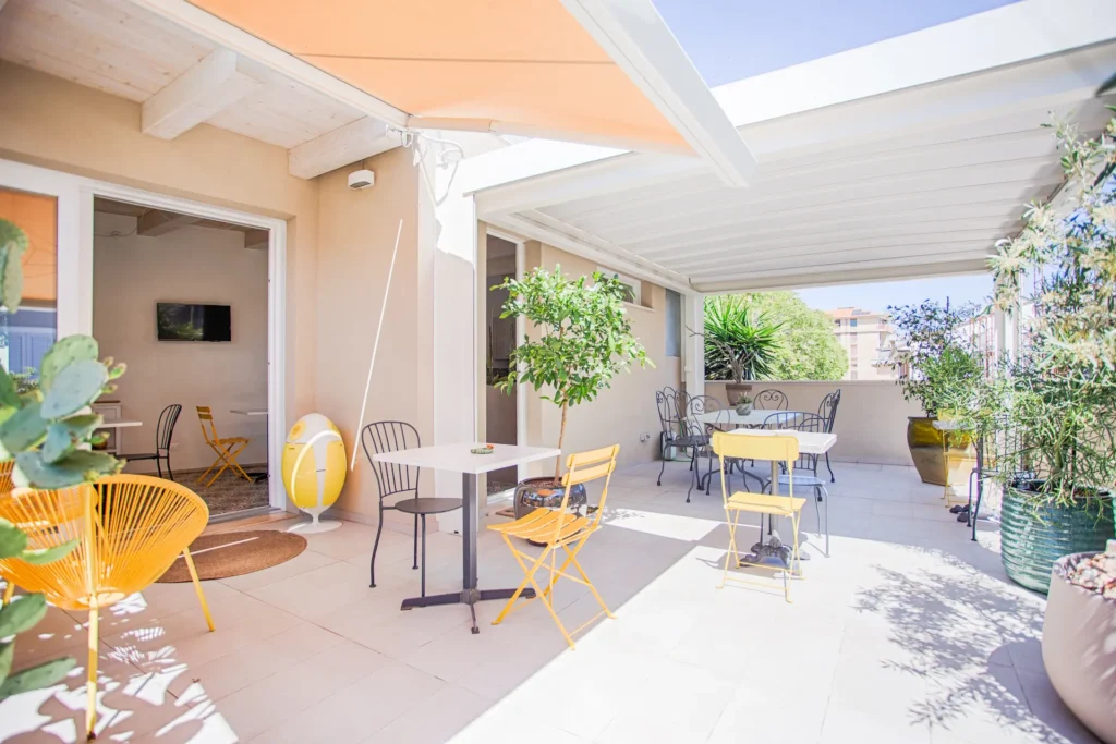 Terrazzo panoramico attrezzato del B&B Fontanella 32 a Porto Sant'Elpidio con tavolini, sedie colorate, tende da sole e piante per colazioni all'aperto.